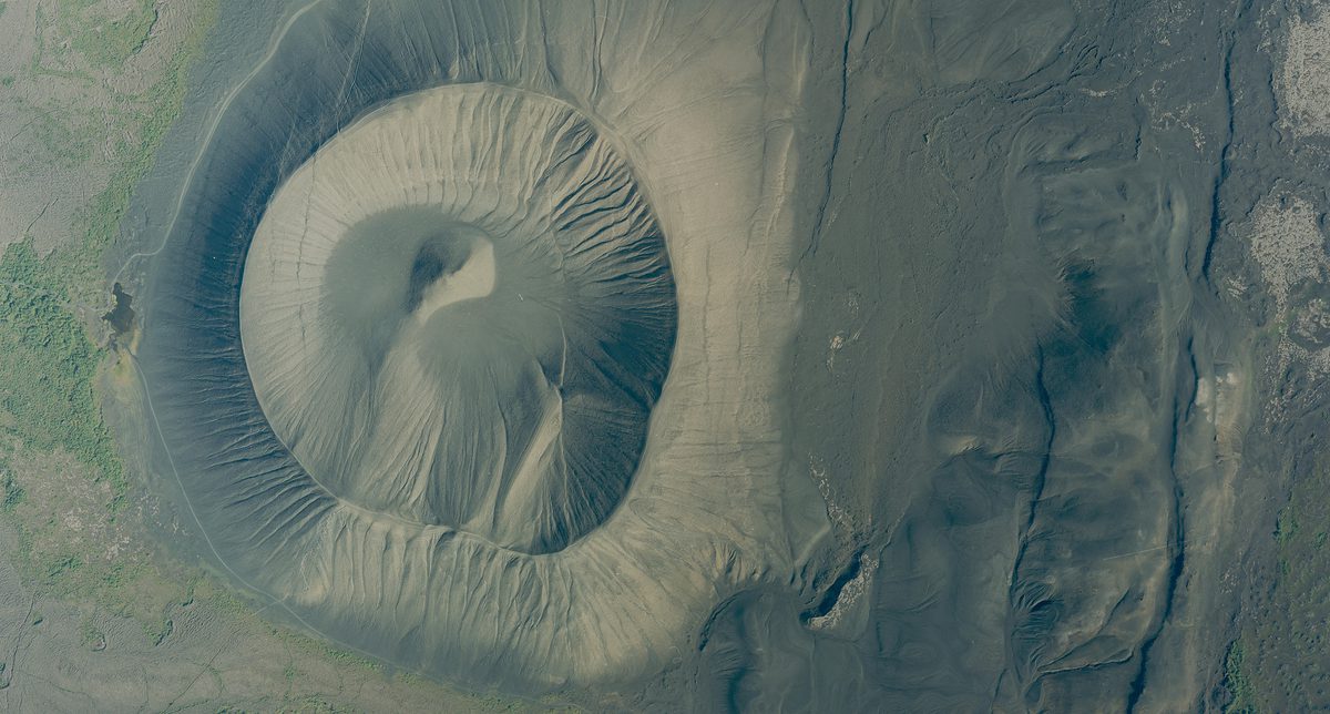 A historic colour vertical aerial photo of a volcanic crater. The surface of the crater looks gritty and dusty.