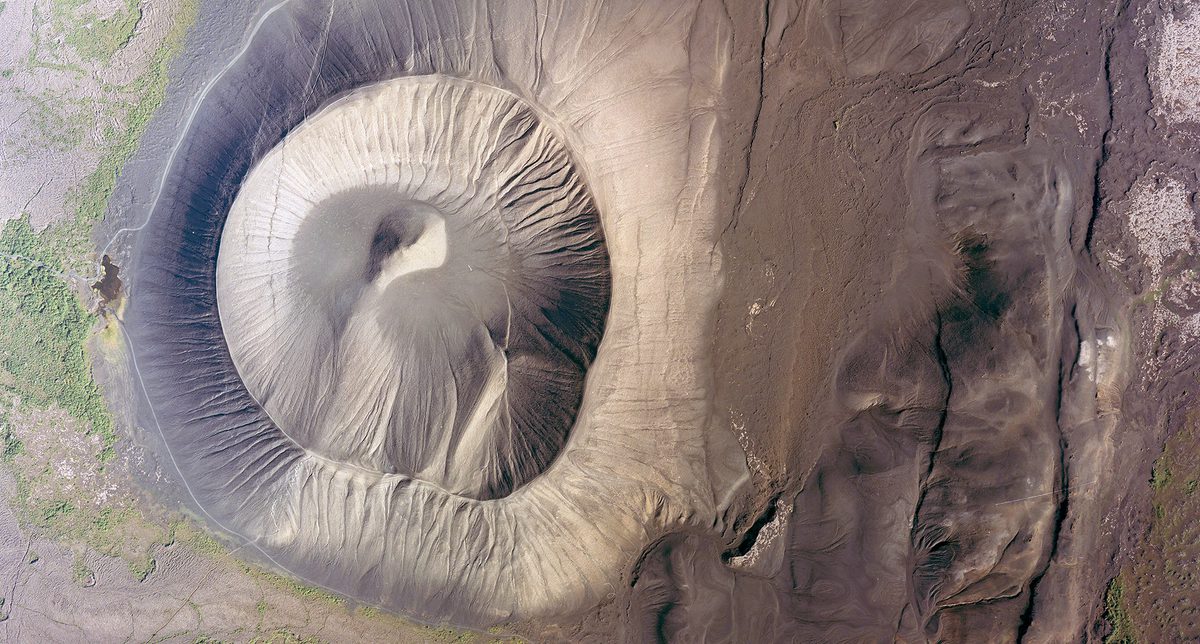 A historic colour vertical aerial photo of a volcanic crater. The surface of the crater looks gritty and dusty.