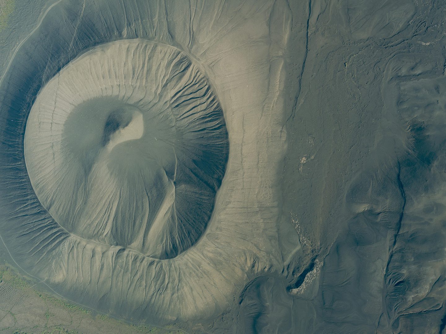 A historic colour vertical aerial photo of a volcanic crater. The surface of the crater looks gritty and dusty.