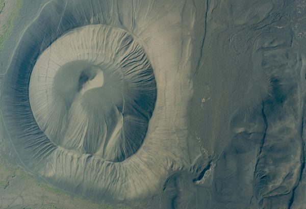 A historic colour vertical aerial photo of a volcanic crater. The surface of the crater looks gritty and dusty.