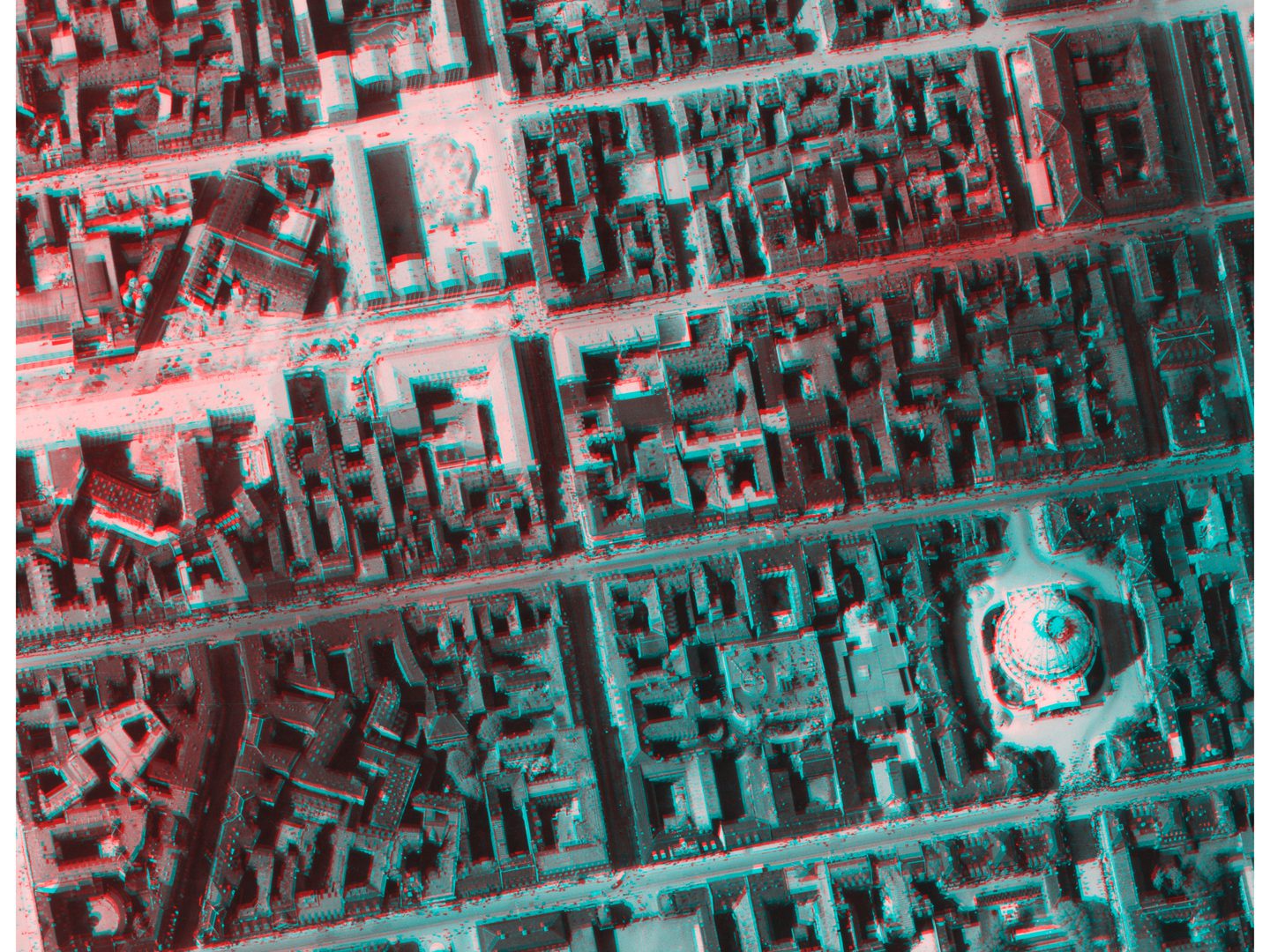 An image in blue and red tones of a city seen from above. The street grid is clear, as is a large domed building bottom right. The image is formed from 2 historic vertical aerial photos.