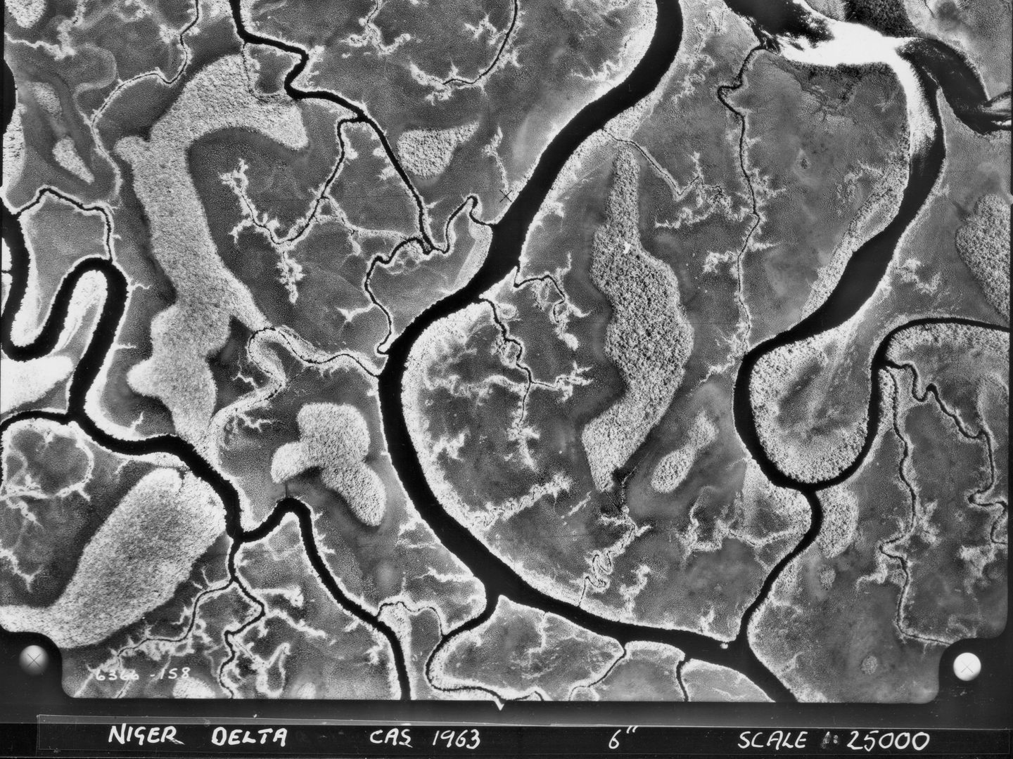 A black and white aerial photo of a river delta. A complex pattern of watercourses wind their way through wetlands. The 2 main channels runs vertically through the right side of the image. Data about the image is written along the bottom edge.