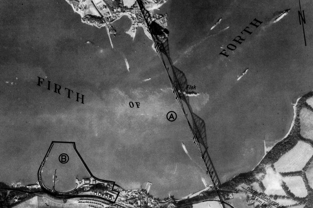 A black and white annotated aerial photo of the Forth Rail Bridge. The bridge and its shadow span the image vertically. The words ‘Firth of Forth’ have been written across it and the word ‘Flak’ in the middle marks the location of anti-aircraft guns.