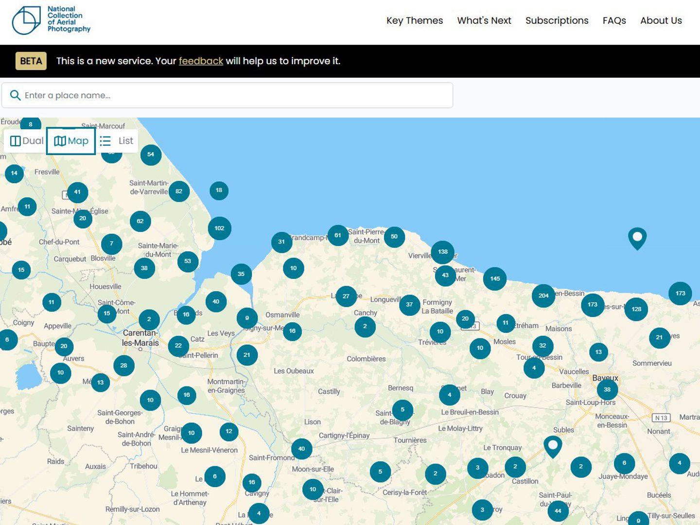 A screenshot of the NCAP Air Photo Finder. It shows a map with numerous blue dots covering it. Each dot contains a number reflecting how many images are visible for that area. The NCAP logo is visible top left.