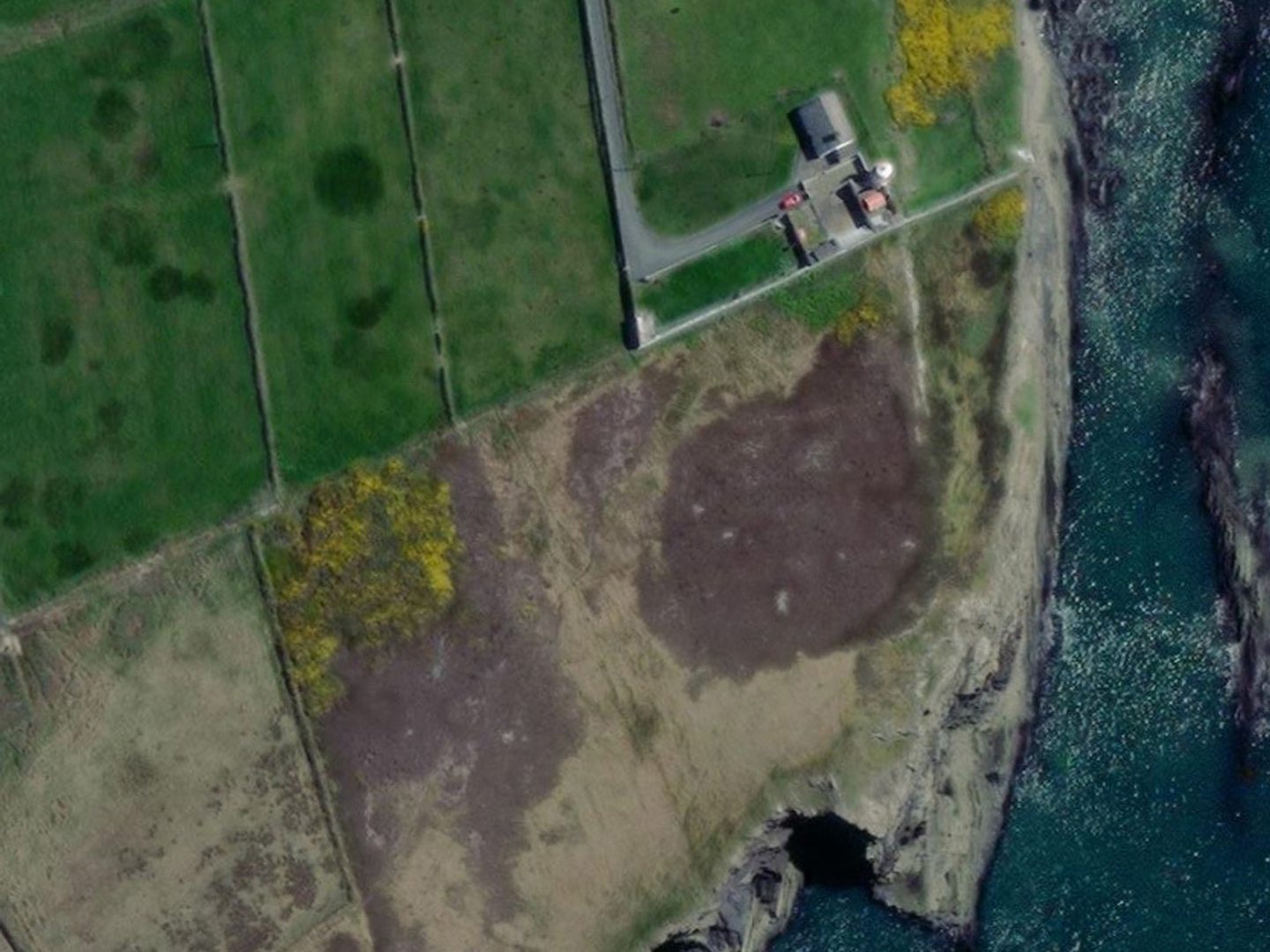 A contemporary colour satellite image of the same coastline as the previous image. The letters '7 EIRE' are now no longer visible in the grassy area.